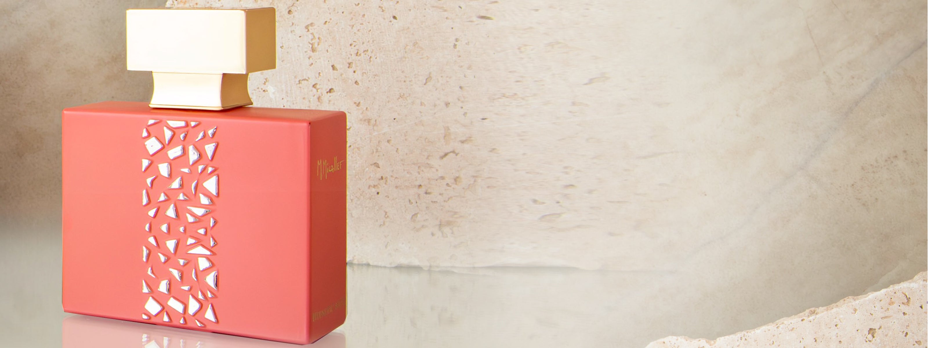 Flacon du parfum Hypnotic Musk M.Micallef, au design rose mat et détails dorés, posé sur un fond minéral beige.